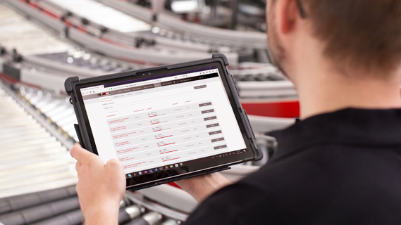 look over a man's shoulder at a tablet running a warehouse software