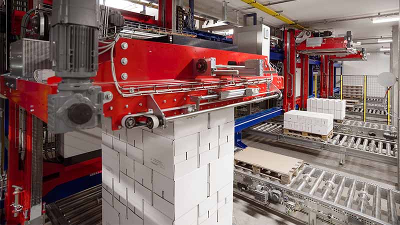 A large red robot stacks milk cartons on pallets