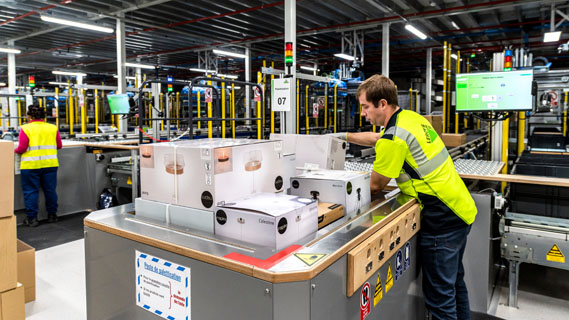 Warehouse worker operating the palletizing machine, forming boxes into a pallet