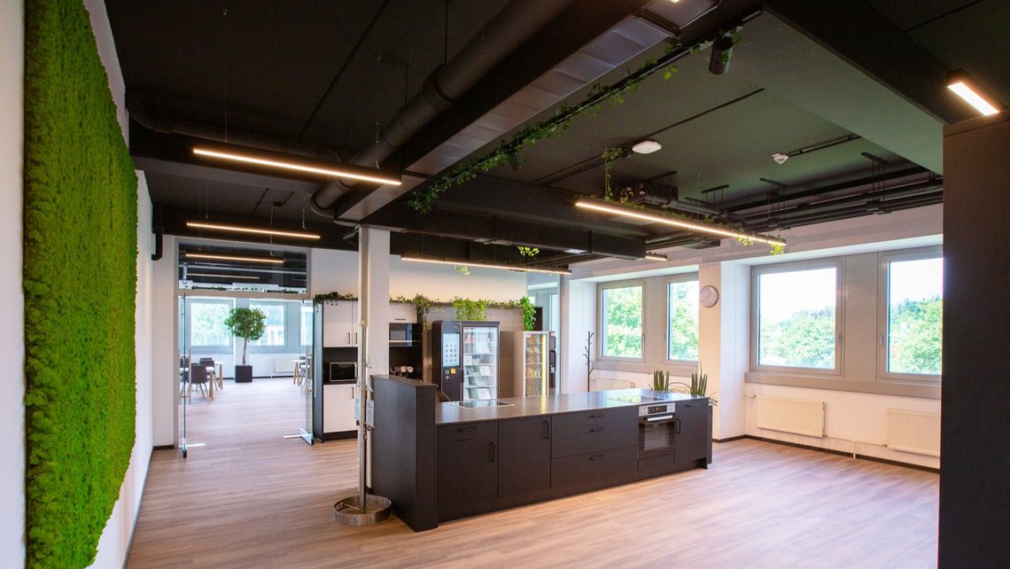 Our Canteen at TGW Robotics in Rohrdorf with a moss-wall and kitchen island.