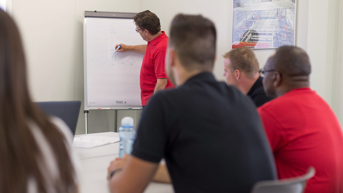 Man drawing a technical idea on a flipboard for employees, as part of training services for a customer