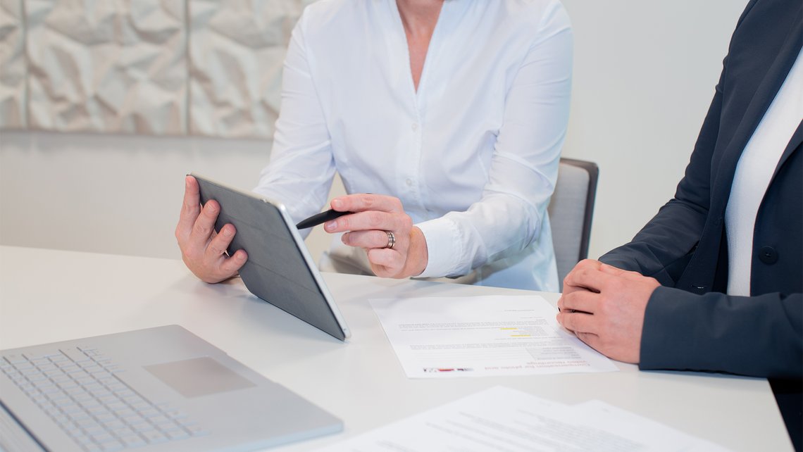 Two people discussing behind a tablet