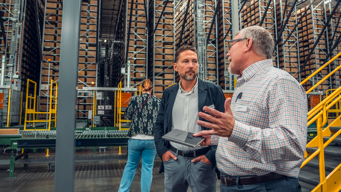 Attendees of Gap Campfire Talk having a discussion near TGW Logistics' mini load ASRS system aisles