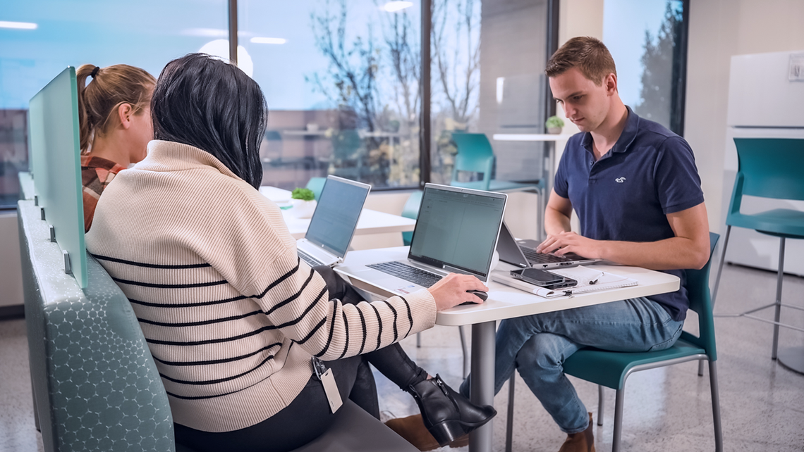 Three TGW Logistics' employees working at a table in the breakroom