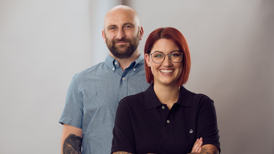 Two TGW Logistics employees smiling and posing for a picture