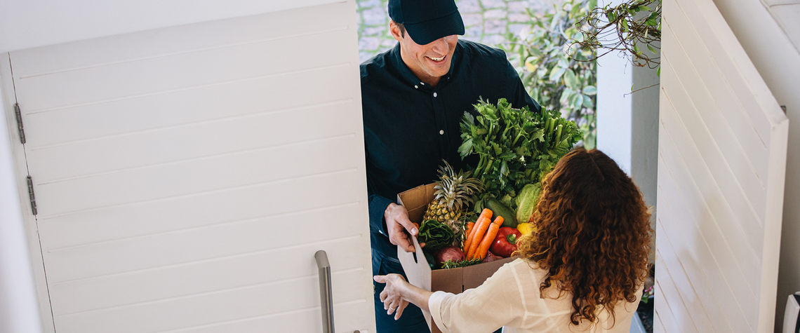 Woman receiving an ecommerce grocery order delivered to her door. Order includes produce.