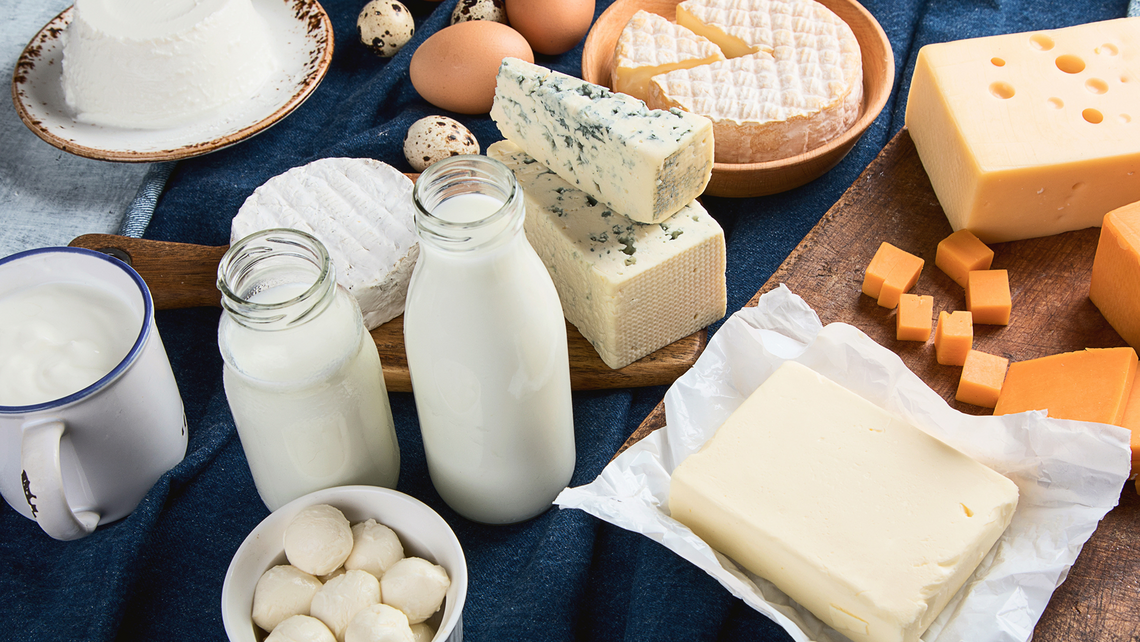 Various milk bottles and cheeses on display on a blue table cloth