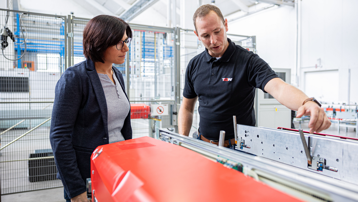 A TGW Logistics' Distributor Business Unit employee showing a warehouse automation systems integrator client how the Stingray shuttle works