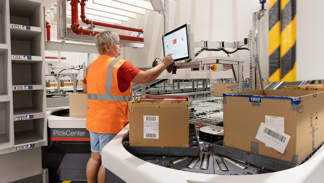 Woman using a PickCenter One workstation for split case order picking in the Puma distribution center