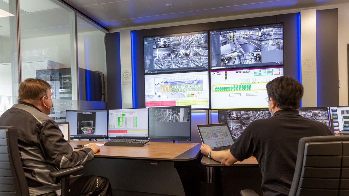 Two employees operating the warehouse management system at Puma in the control room behind several screens