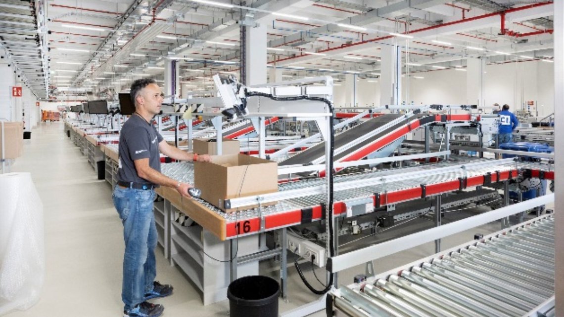 [Translate to France:] A worker at a warehouse picking station