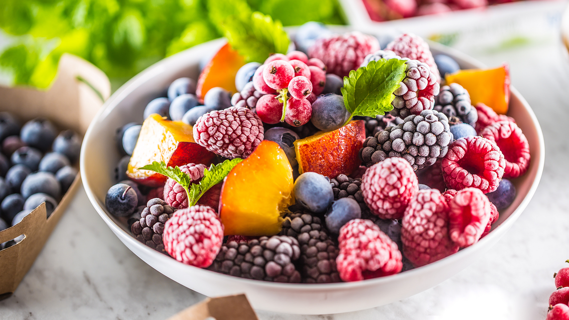 Close up of a bowl of frozen fruit and other containers of fruits that require strong cold chain logistics