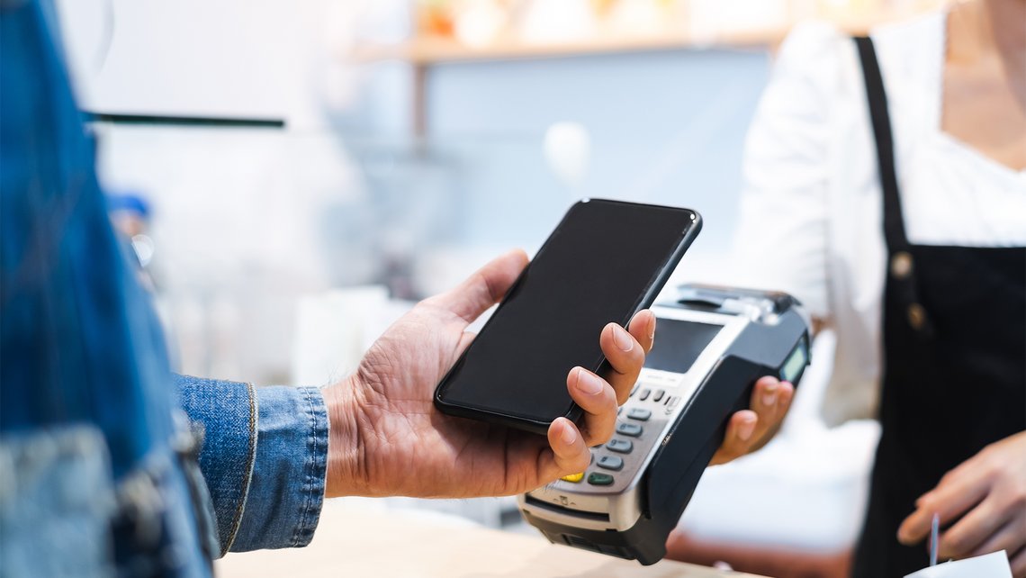 [Translate to France:] A man pays with his cell phone in a shop