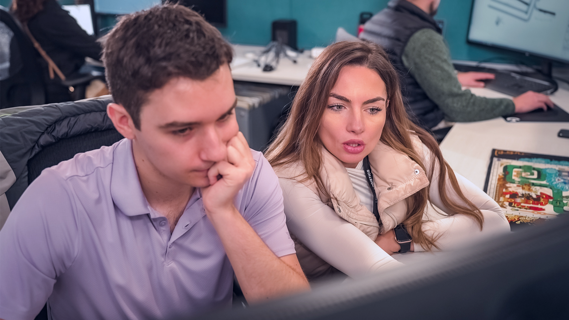 Two TGW Logistics' employees looking at a computer screen and problem solving together