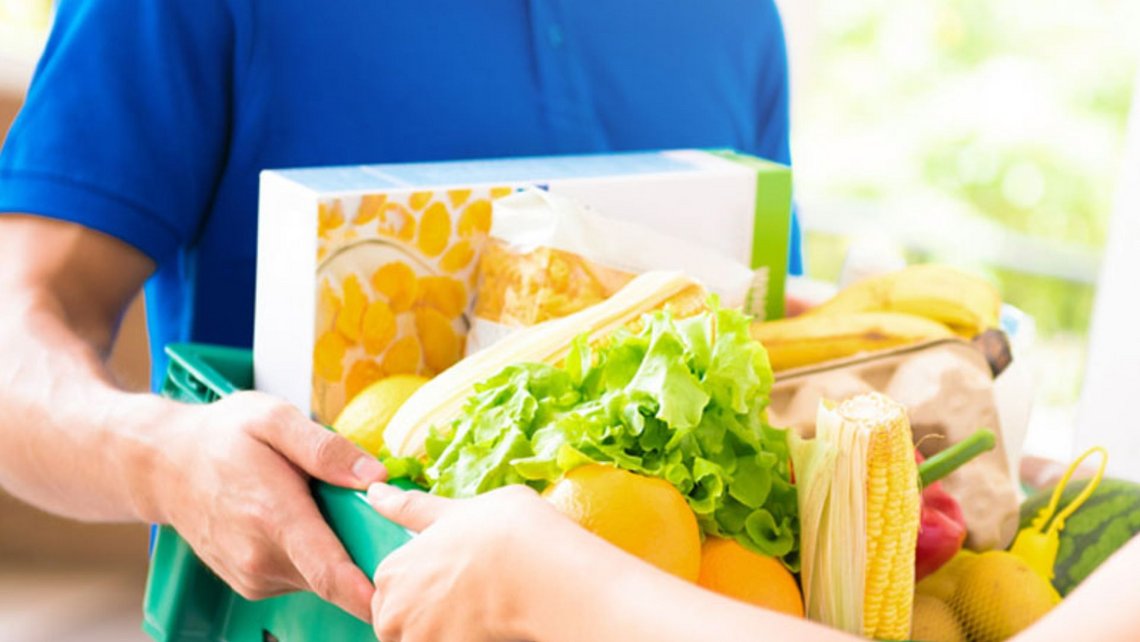 Man bringing groceries home in a full basket with lettuce and bread on top