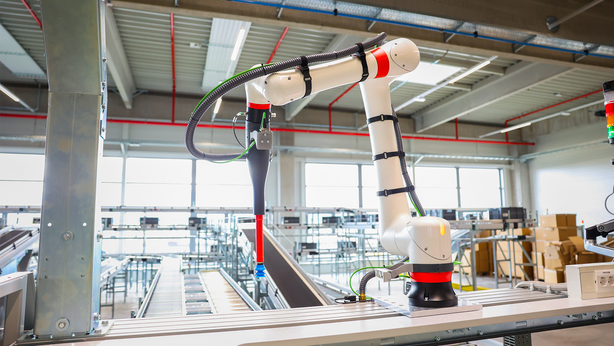 View of TGW Logistics' RovoFlex robotic picking arm at a PickCenter One workstation inside a warehouse facility