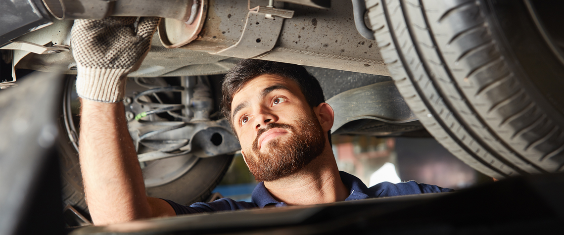 Mechanic working on the underbody of a car