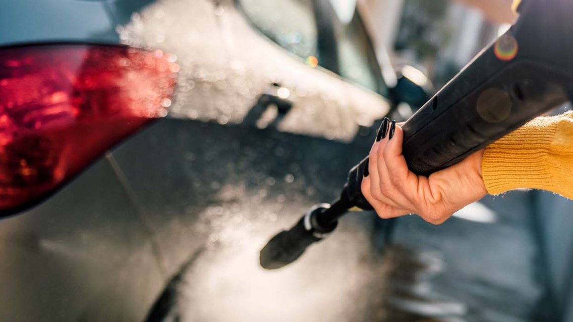 Man cleaning his car with a high-pressure cleaner