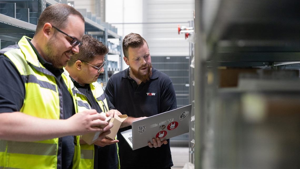 Three men looking through space parts storage at a customer's site