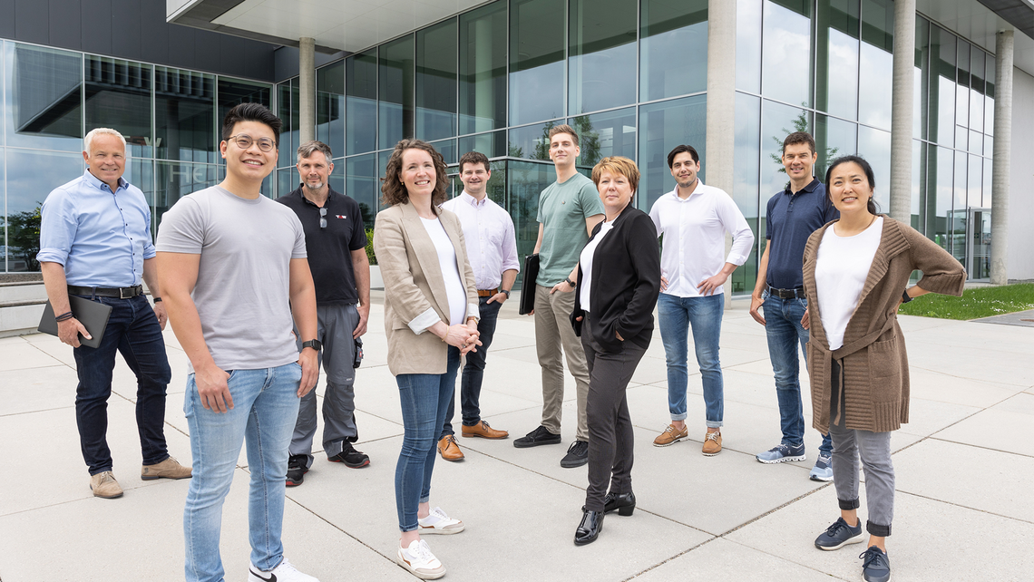 Group of diverse TGW Logistics employees standing outside the global headquarters. This is Team Possible for warehouse automation.