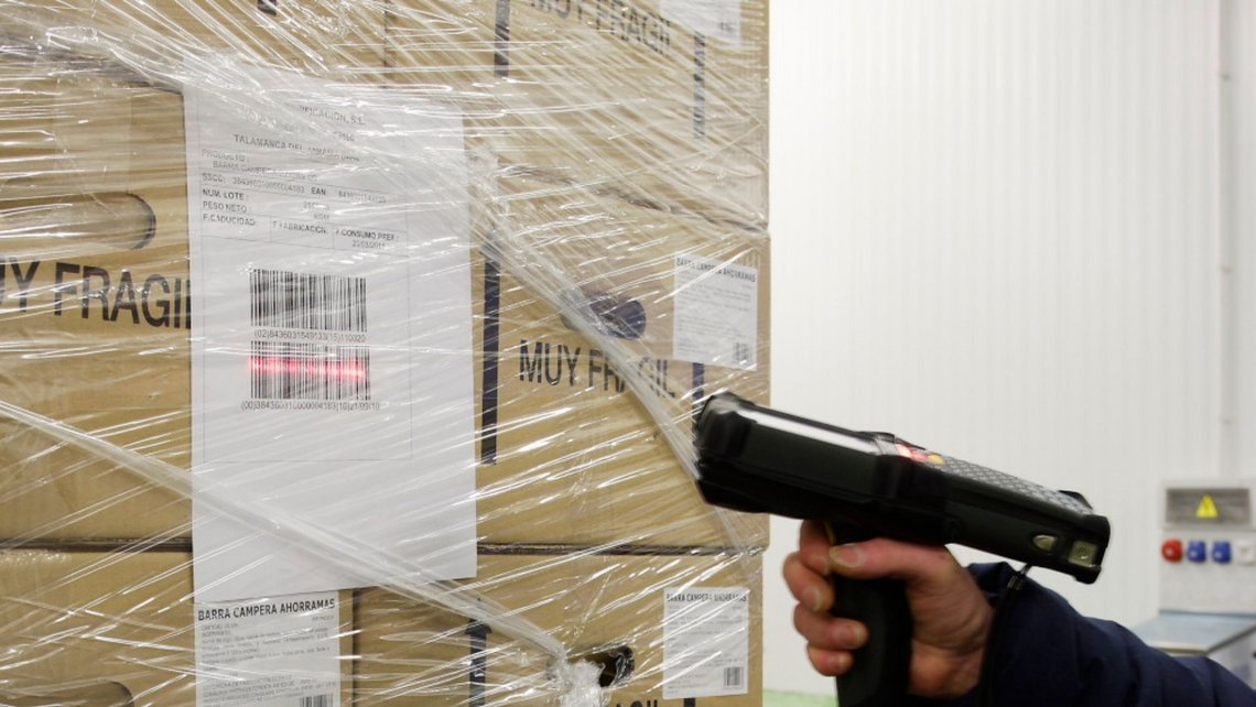 A man holding a scanning device, scanning the barcodes on incoming goods