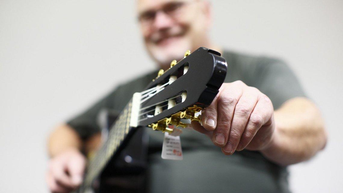 Man tuning a black acoustic guitar