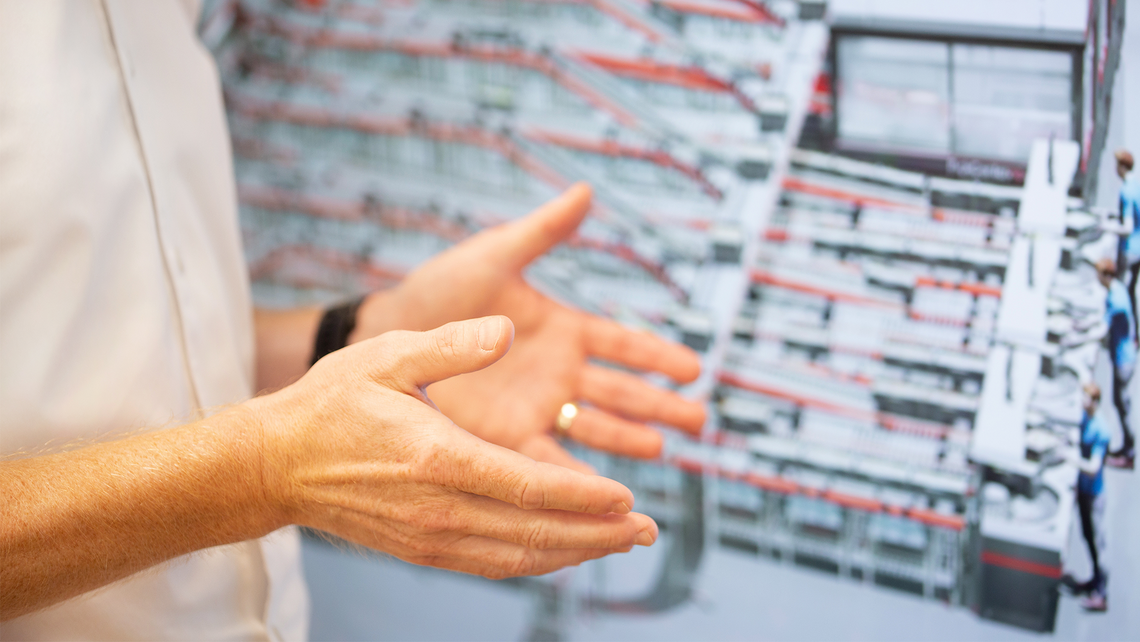 TGW Logistics' employee's hands in front of a screen, presenting the FlashPick solution for flexible logistics