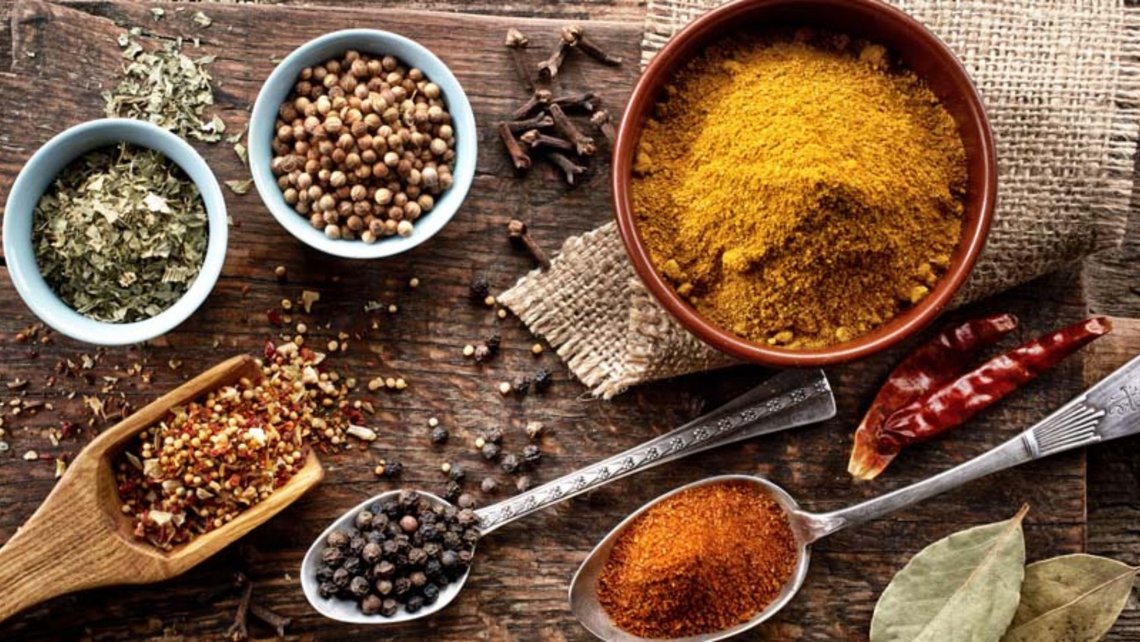 Mixed colorful spices in bowls and on spoons