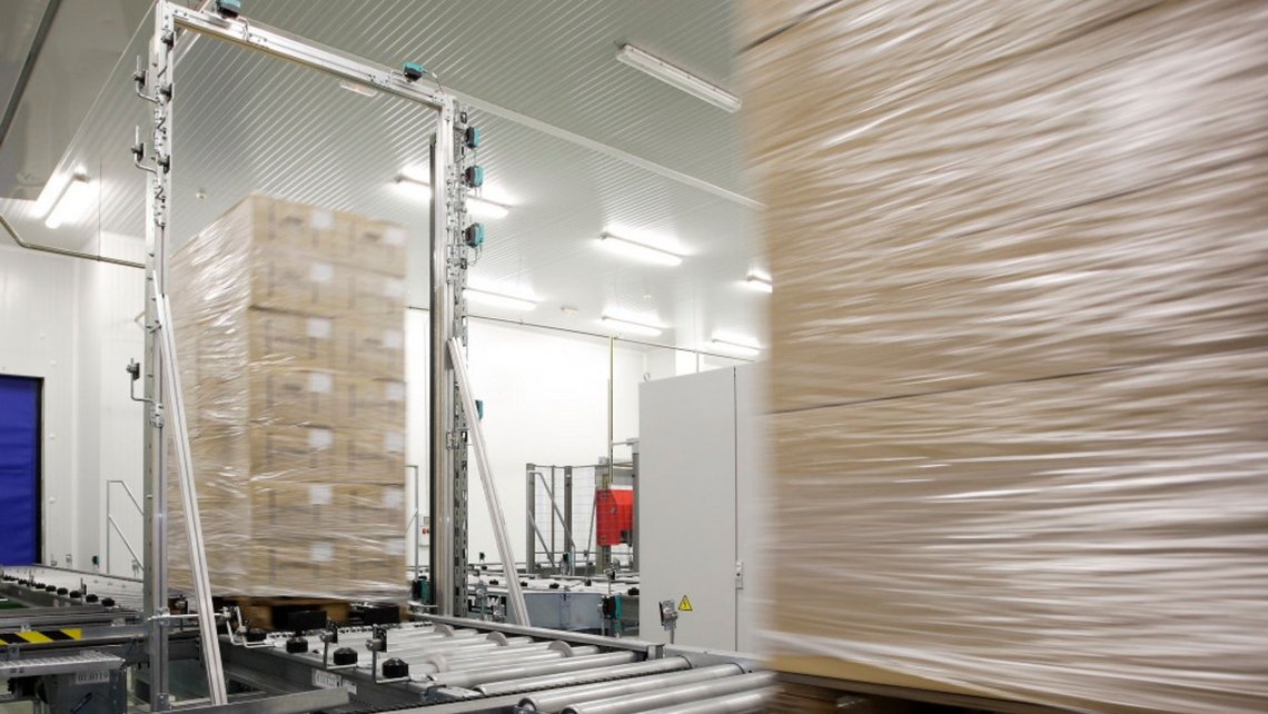 Pallets with boxes containing fresh goods on a conveyor belt