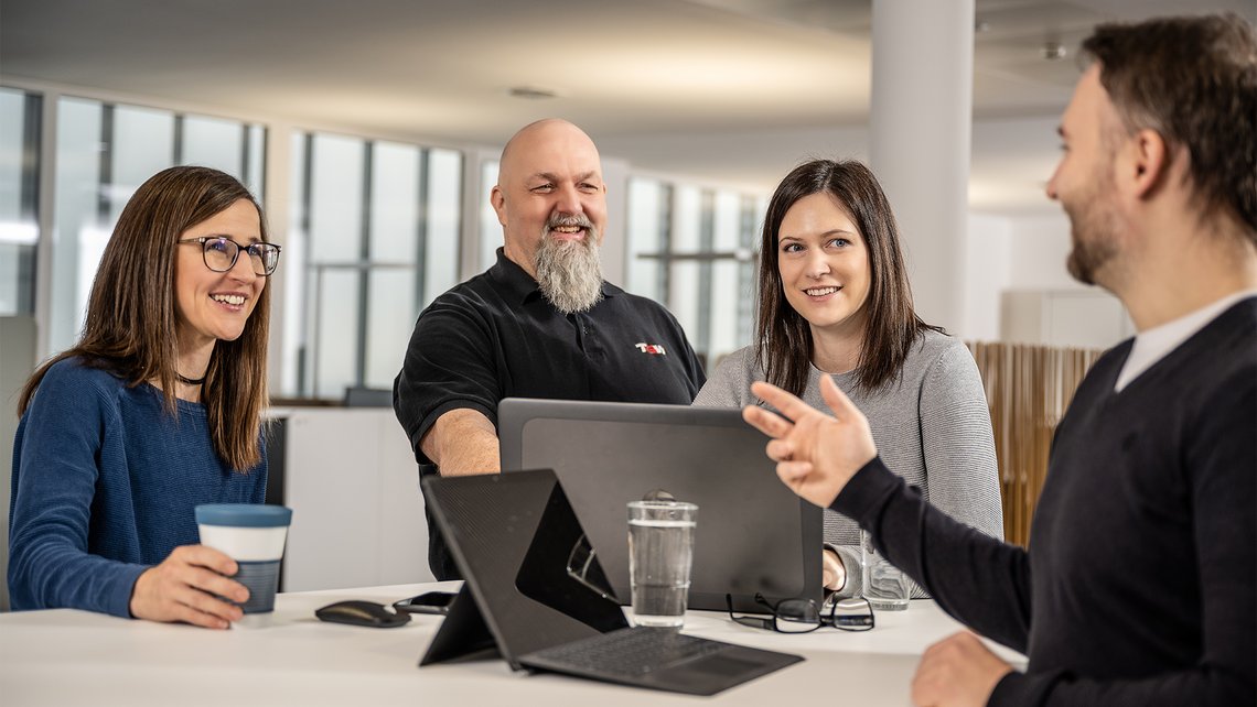 Team meeting with four colleagues at the office with everyone smiling