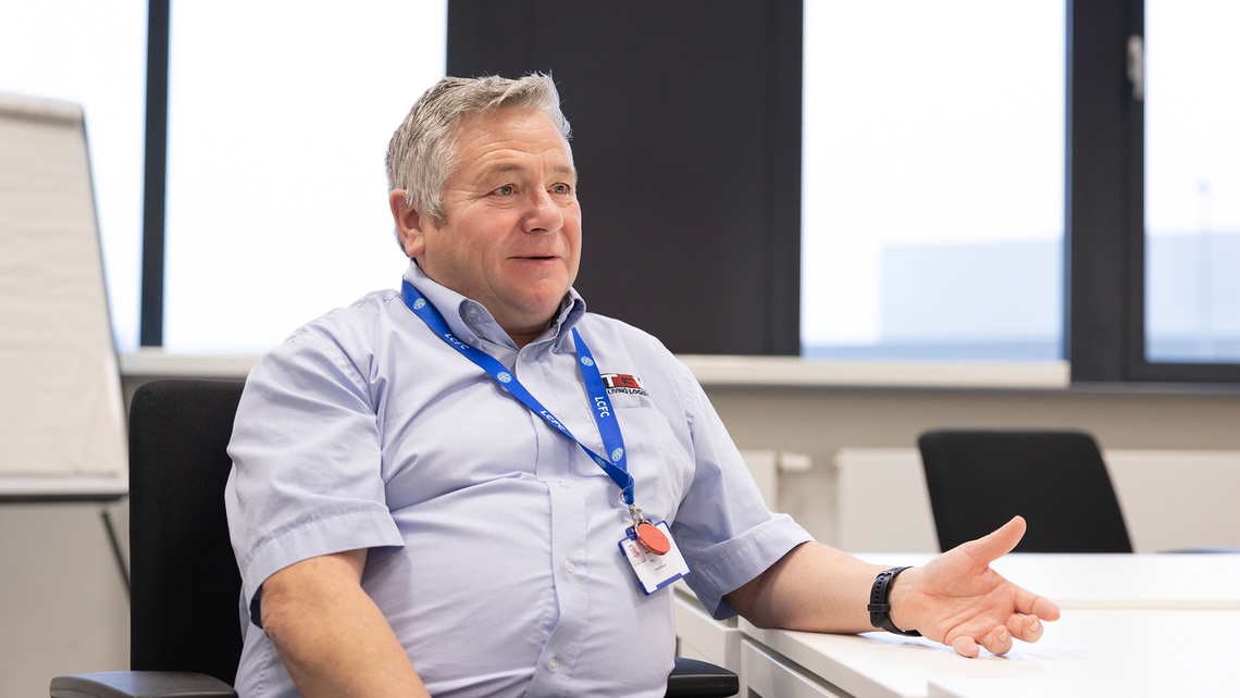 TGW Logistics employee that works at a highly automated grocery logistics center talking in a conference room with the client