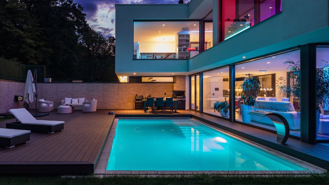 A luxurious property at night, with pool, modern architecture and atmospheric lighting